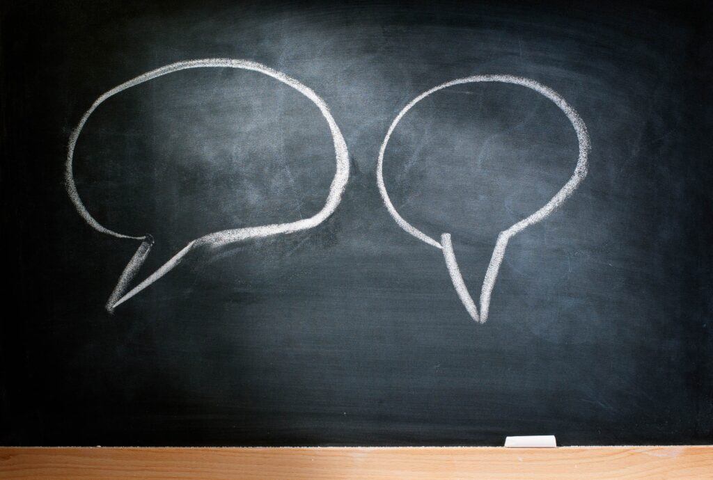 two speech bubbles on a black chalkboard